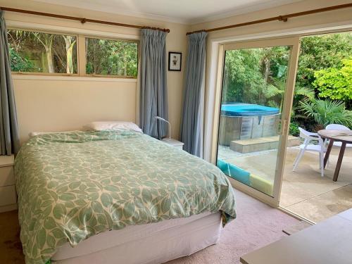 une chambre avec un lit et une porte coulissante en verre dans l'établissement Private Coastal Sanctuary - 50m from Stunning Beach!, à Whakatane