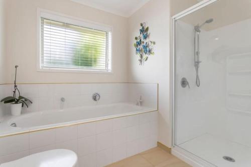 une salle de bain blanche avec une baignoire et une douche dans l'établissement Private Coastal Sanctuary - 50m from Stunning Beach!, à Whakatane