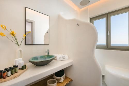 a white bathroom with a sink and a tub at Acro Caldo Suites in Akrotiri