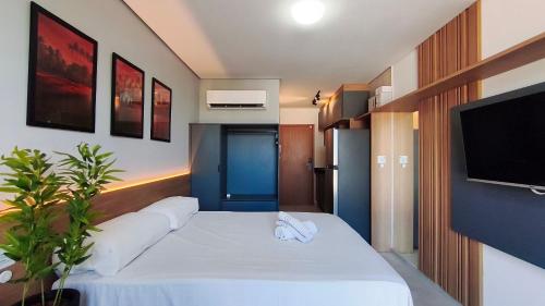 a bedroom with a white bed with a flat screen tv at Acqua Beach Residence by CTA in Tamandaré