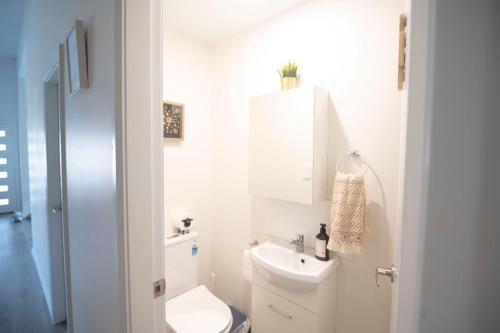 a white bathroom with a toilet and a sink at Tranquil 3-Bed Home Pet-friendly Retreat with Community Pool in St Georges Basin