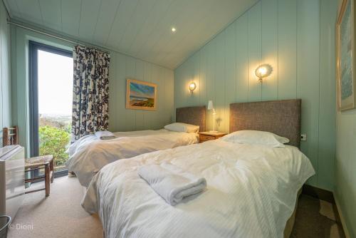 twee bedden in een kamer met een raam bij Aberdaron-Lodge in Aberdaron