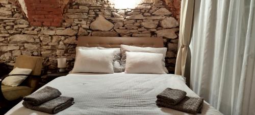 a bedroom with a bed with pillows and a stone wall at Statek Kloubek in Chabičovice