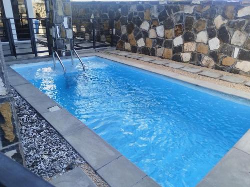 a large blue swimming pool with a stone wall at residence exotica in Île aux Chats
