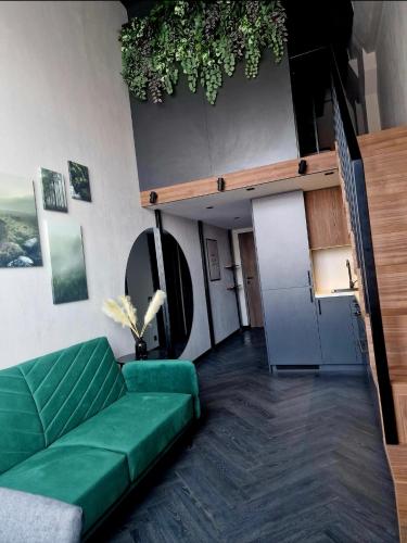 un salon avec un canapé vert et une cuisine dans l'établissement Stylish loft, à Vilnius