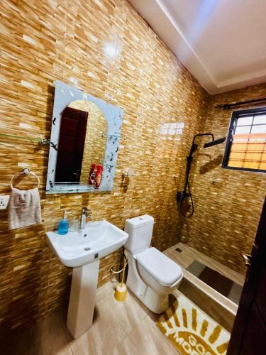 a bathroom with a sink and a toilet and a mirror at Modern 2-Bedroom Apt with African Vibe- Cape Coast in Cape Coast