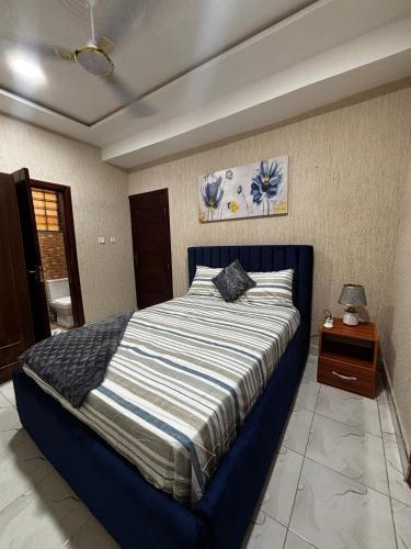 a bedroom with a large bed with a blue frame at Modern 2-Bedroom Apt with African Vibe- Cape Coast in Cape Coast