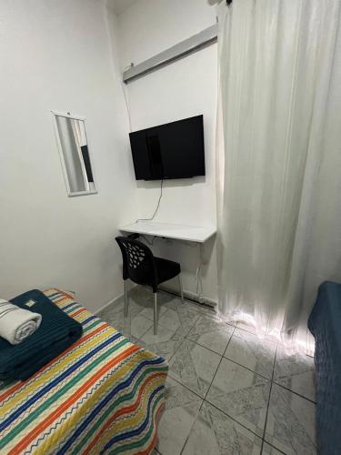 a bedroom with a desk with a television and a bed at Cantinho aconchegante - Quarto 09 - AR-condicionado in Bayeux