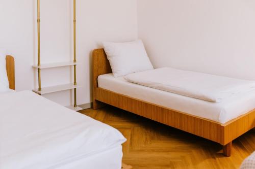 two beds in a room with a bench with a pillow at JUGA Apartmány in Jaroslavice