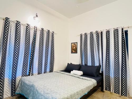 a bed in a room with blue and white curtains at Lima Beach House Varkala in Varkala