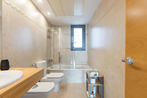 a bathroom with a tub and a toilet and a sink at Loft moderno con terraza y piscina en Valencia in Burjasot