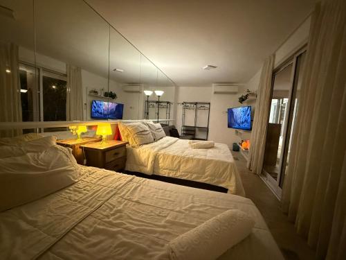 a hotel room with two beds and a mirror at Charmosa hospedagem no Jardim Secreto SP in Sao Paulo