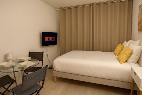 ブローニュ・ビヤンクールにあるSUNNY Studio 2 steps from metroのベッドとテーブルとテレビがあるホテルの部屋