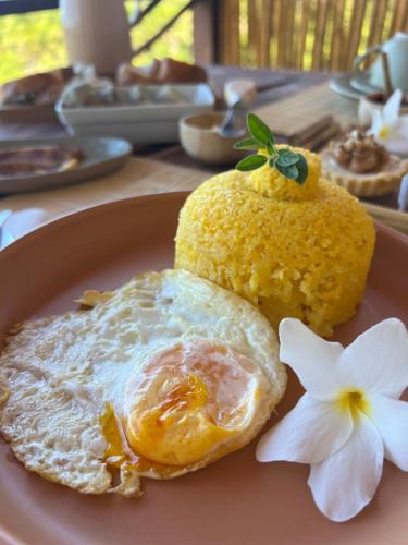 a fried egg and a pineapple on a plate with a flower at Almaré Hospedagem - Boipeba in Cayru