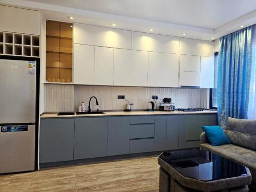 une cuisine avec des placards blancs et un canapé dans le salon dans l'établissement Premium apartment in Batumi 1718, à Batoumi