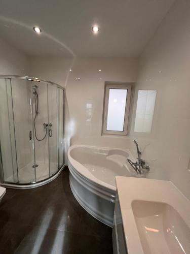 a bathroom with a tub and a shower and a sink at Domy całoroczne Cieszyno in Cieszyno