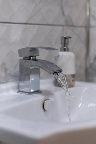 a bathroom sink with water running from a faucet at Cosy Clay Home, Near Airport, NEC, City Centre in Birmingham