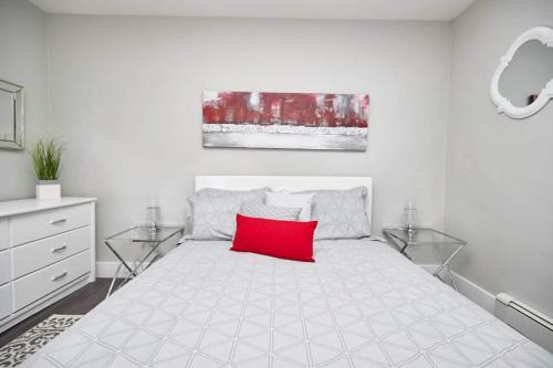 Un dormitorio blanco con una almohada roja sobre una cama. en Clifton Hill Hideaway 2b -two Bedroom Condo, en Niagara Falls