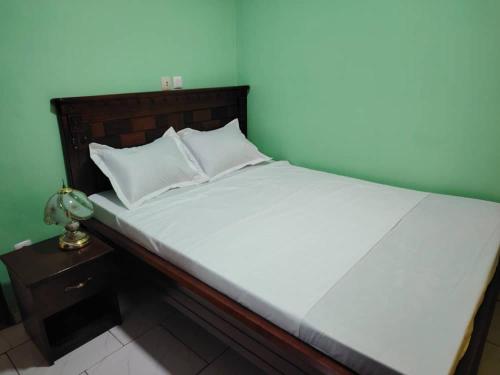 a bed with white sheets and a wooden headboard at Euro Modern Studios Nkoabang-Yaounde in Yaoundé