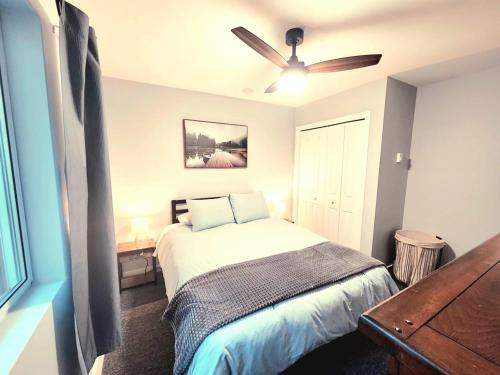 een slaapkamer met een bed en een plafondventilator bij Modern 2BR SPA Retreat in Shawnigan Lake