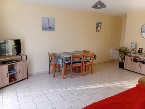 een woonkamer met een tafel en stoelen en een televisie bij Logement Soulac sur mer in Soulac-sur-Mer