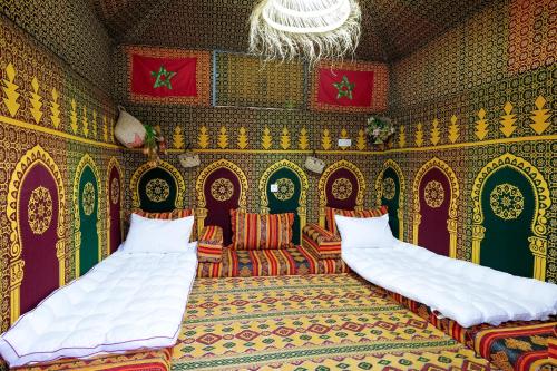 een kamer met 2 bedden, een bank en een kroonluchter bij Studio traditionnel amazigh marocain in Benguerir