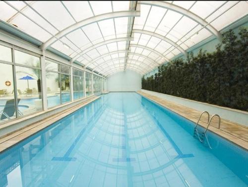 a large swimming pool with a glass ceiling and a swimming pooliteratorhaarhaarhaar at Conforto Flat Hotel Vila Olimpia in São Paulo