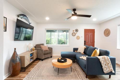 a living room with a blue couch and a ceiling fan at Dog Friendly - 8min to Downtown - FAST Wifi in St Petersburg