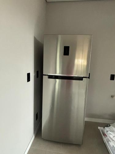 a stainless steel refrigerator sitting in a room at Tua Casa no Rosa in Imbituba