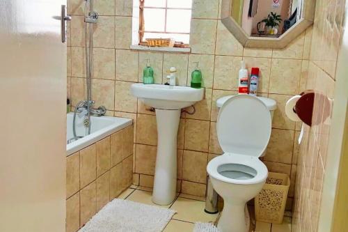un baño con inodoro y lavabo en Budget Stays at Olivia Pines Guesthouse, en Krugersdorp