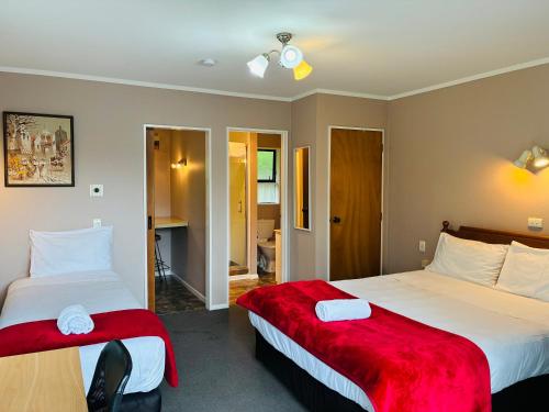 パーマストンノースにあるAwatea Park Motelのホテルルーム ベッド2台&赤毛布付