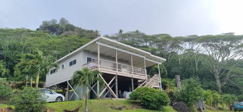 a house on a hill with a car parked in front at Ocean Beach Town View - Infinity Pool in Avarua