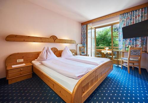 a bedroom with a bed and a balcony with a table at Hotel Schwaiger in Eben im Pongau