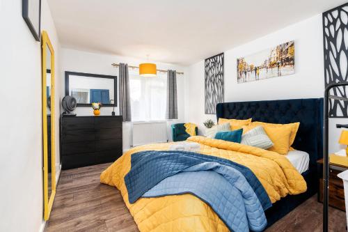 a bedroom with a bed with a blue and yellow comforter at The Cozy Corner near NEC Birmingham Airport Entire Apartment Work Desk in Kingshurst