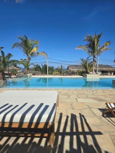 a bed in front of a swimming pool with palm trees at Casitas en Vichayito, a Pasos de la Playa in Los Órganos