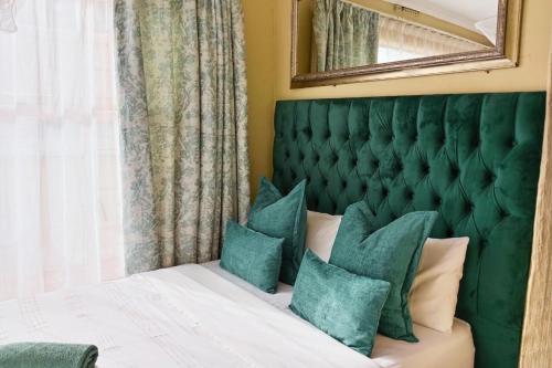 1 dormitorio con cabecero verde y cama con almohadas en Budget Stays at Olivia Pines Guesthouse, en Krugersdorp