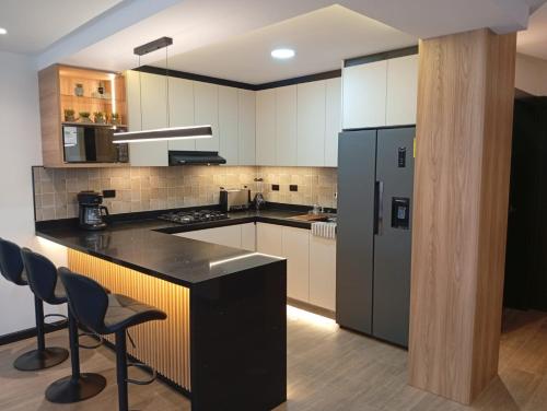 Il comprend une cuisine équipée d'un comptoir noir et d'un réfrigérateur. dans l'établissement Casa Larrea, à Cuenca