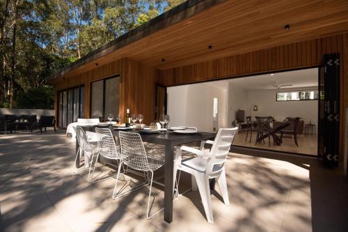 ein Esstisch und Stühle auf einer Terrasse in der Unterkunft Daydream Cottage Beachside Luxury in Lilli Pilli in Surf Beach