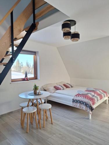 a bedroom with a bed and a table at Manio Pokoje in Bańska Wyżna