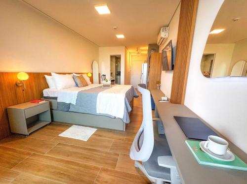 a bedroom with a bed and a desk with a computer at Luxuoso e sofisticado Beach Class Summer by HM in Porto De Galinhas