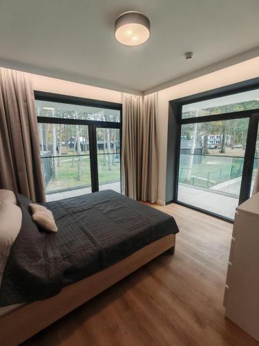 a bedroom with a bed and two large windows at Baltic Jet Silver Sea in Ustronie Morskie