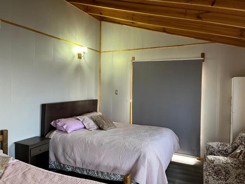 - une chambre avec 2 lits et une chaise dans l'établissement Hostal patronal bypass el rosal k485, à Salto del Laja