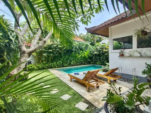 Un jardín con piscina y dos sillas y una casa. en Villa MONTI - LEGIAN - SEMINYAK - Lovely 2 Bedroom Villa - Great Location !, en Seminyak