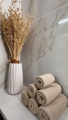 une pile de serviettes sur le comptoir de la salle de bain avec un vase dans l'établissement Luxury Beach Villa 2 min Walk to Sea & Airport, à Meneou
