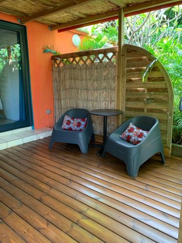 a patio with two chairs and a table on a deck at Les Manguiers in Deshaies