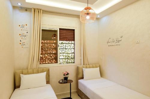 two beds in a room with a window at Riad Bollywood- Prince's Suite in Benguerir