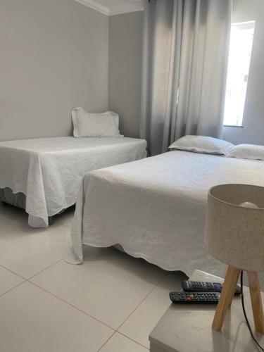 a bedroom with two beds and a lamp and a window at Céu e mar Rua marechal Hermes da Fonseca 37 Praia Grande centro Espaço todo reservado para hóspede in Arraial do Cabo