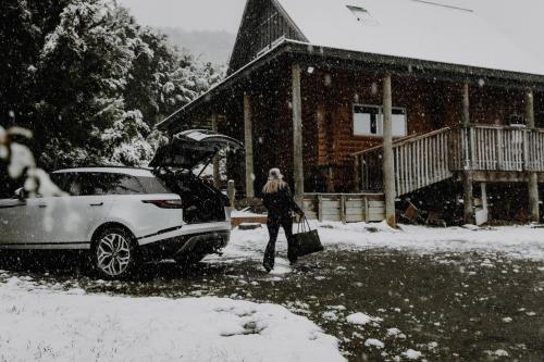 a woman standing next to a car in the snow at Alpine Haven, Peaceful , Stunning Views - ML21396 in Mt Lyford