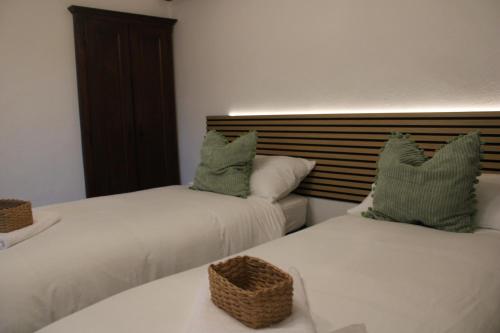 two beds in a room with white sheets and green pillows at La Piazzetta Apartment in Pietralunga