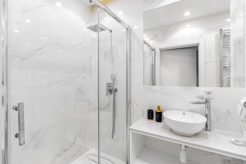 ein weißes Badezimmer mit Waschbecken und Dusche in der Unterkunft Luxury 2-room apartment with a beautiful city view in Warschau